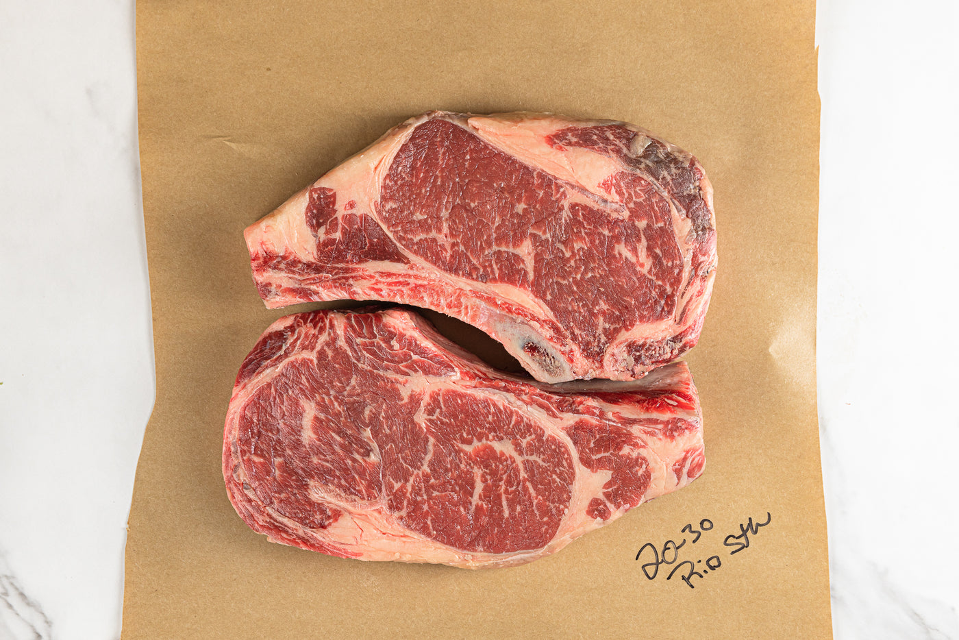Two raw rib-eye steak on butcher paper