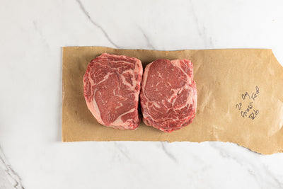 Two grass-fed boneless rib eye steaks on butcher paper
